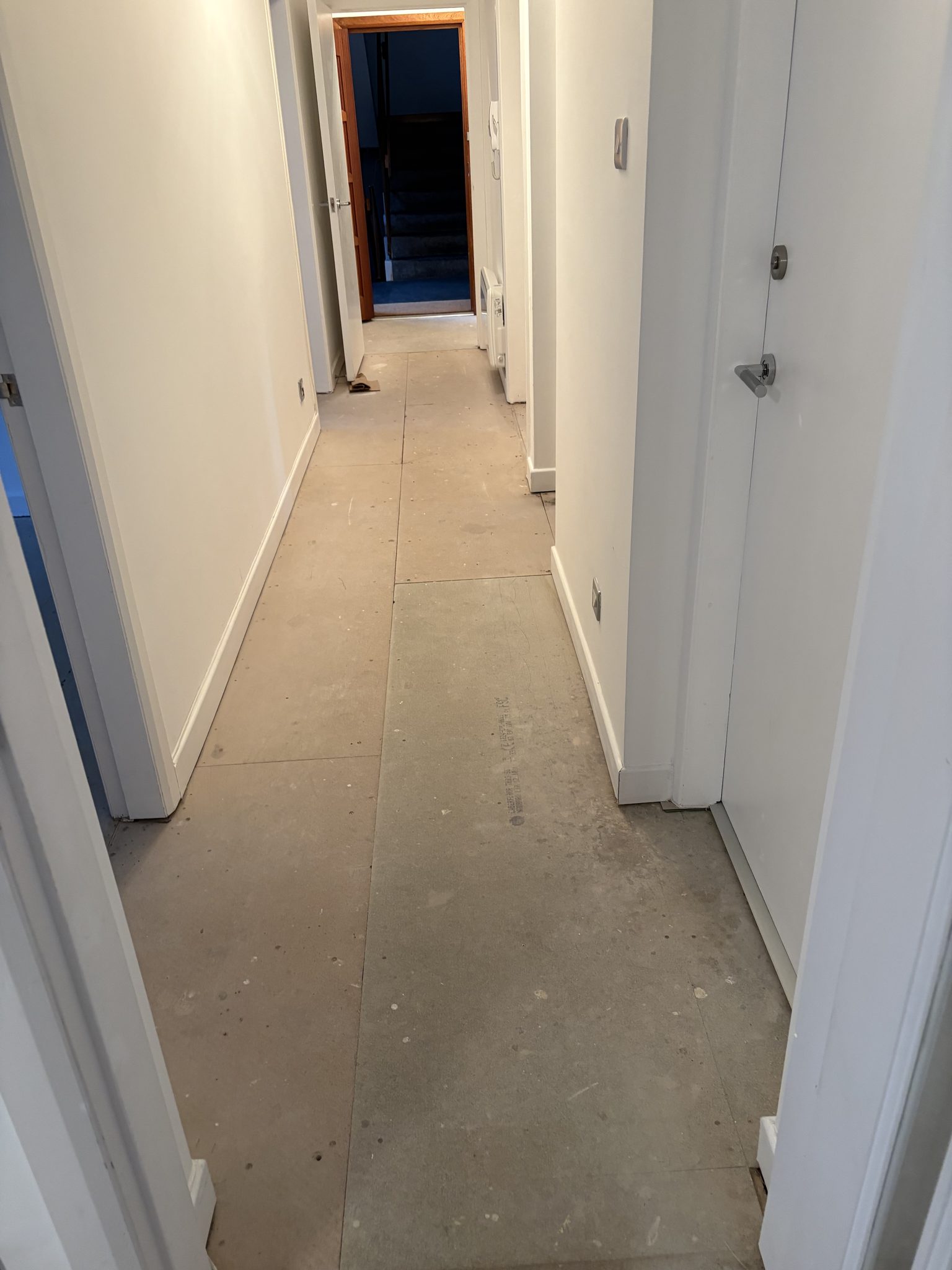 Hallway in Bridge of Allan boarded out ready for flooring, looking through towards the stairs