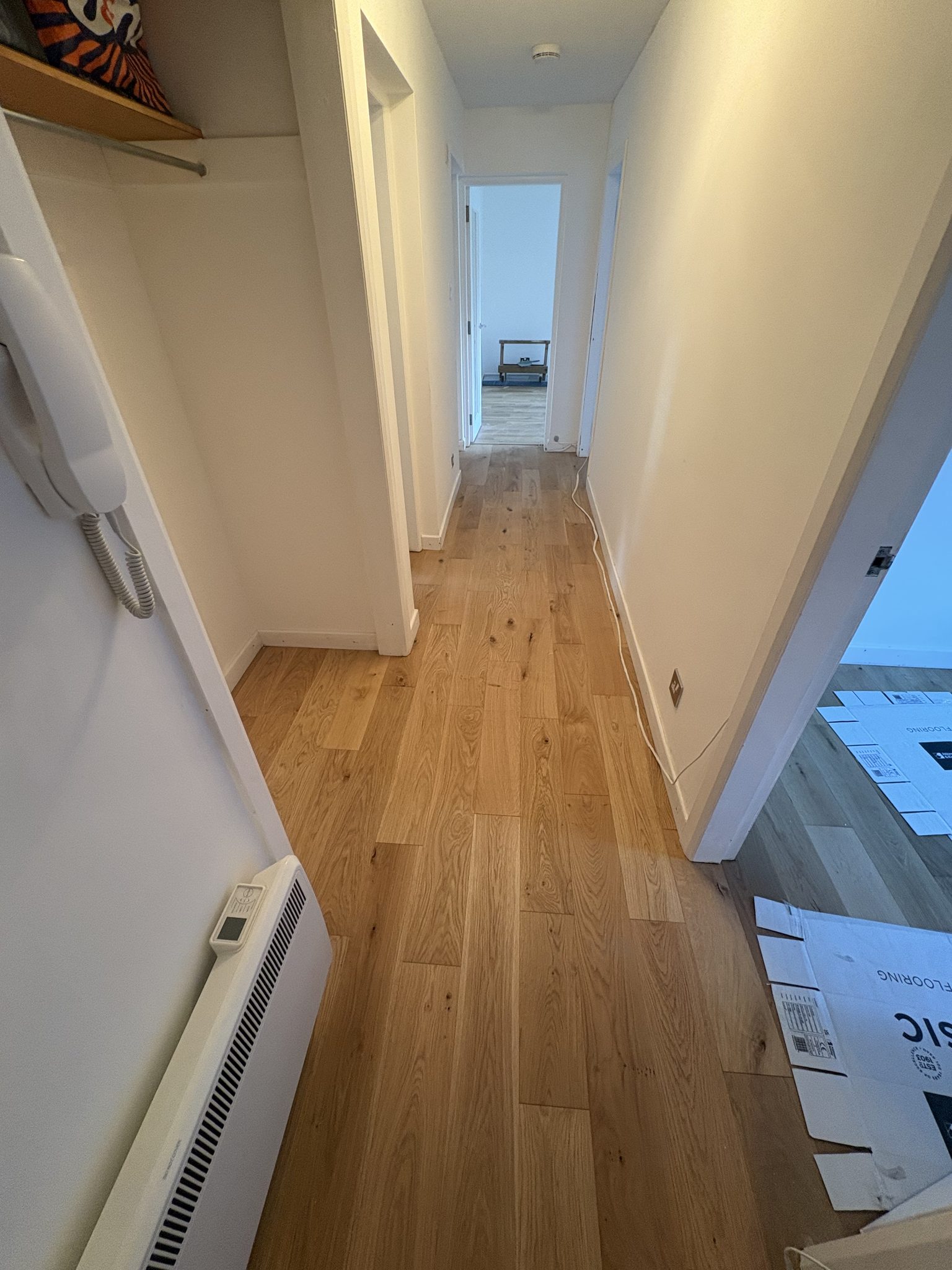 The same hallway with the engineered hardwood boards laid, running through to the room beyond