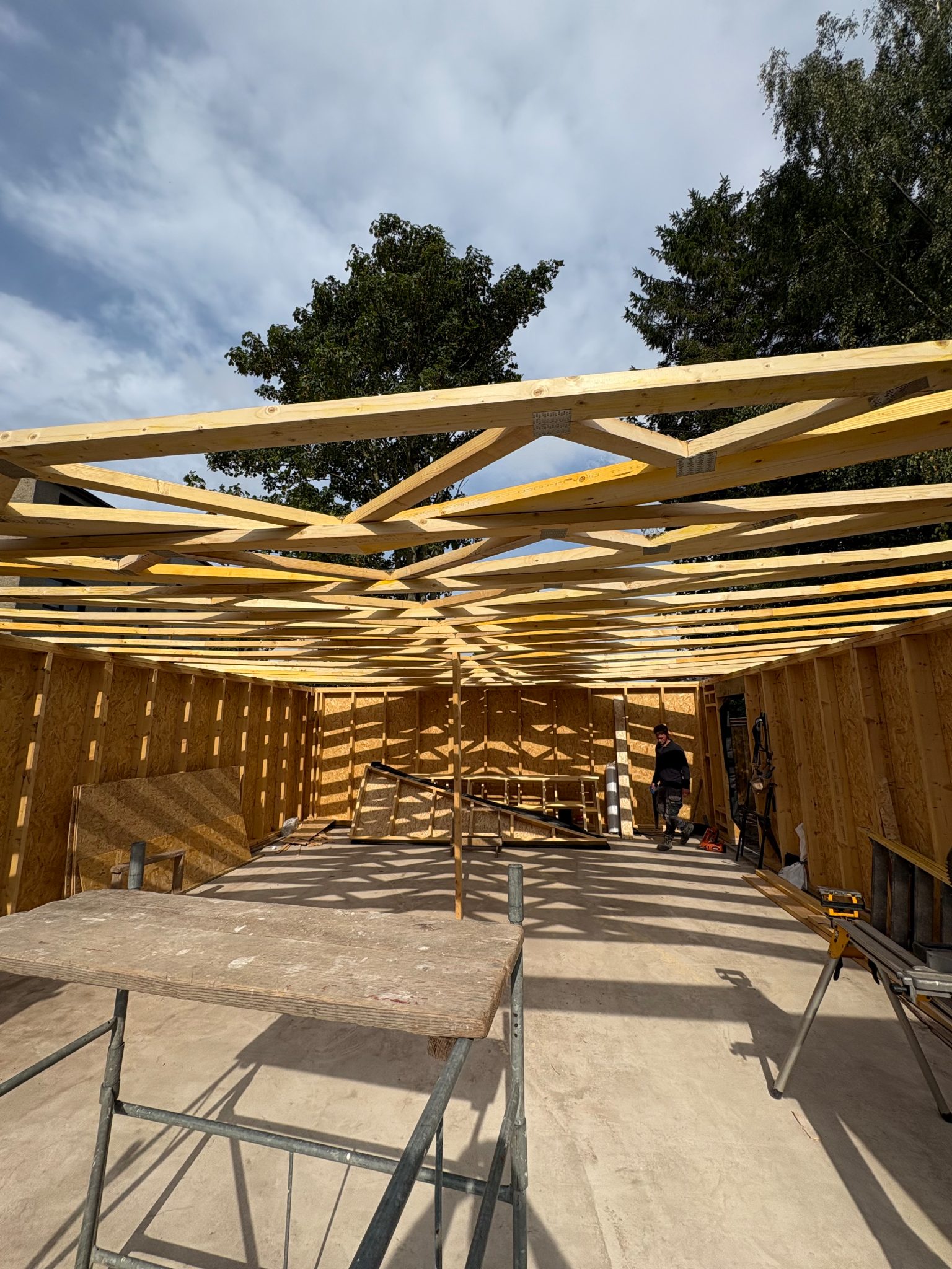 Roof trusses erected over the timber frame of the new garage, with the walls sheathed