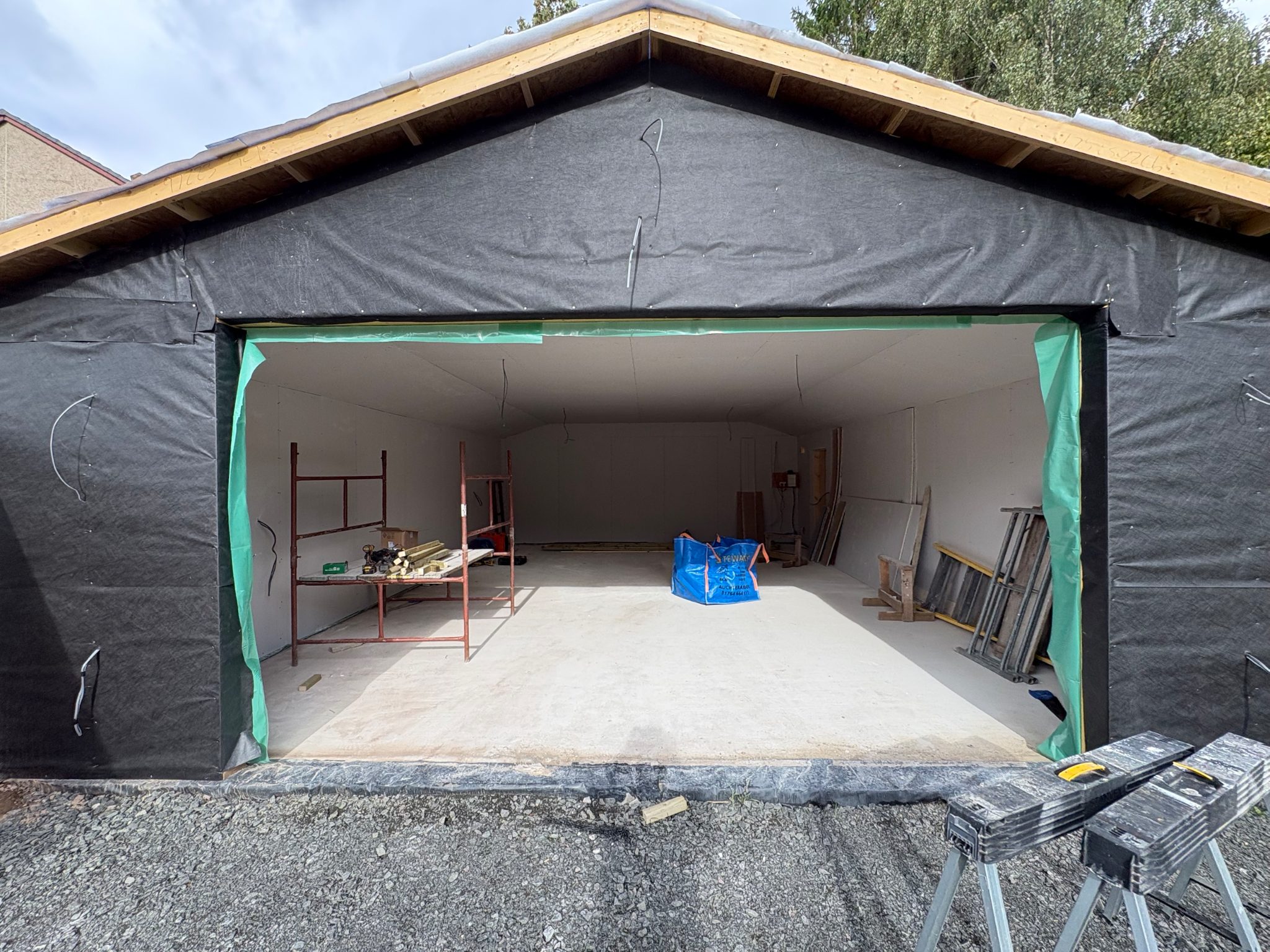The garage at Auchterarder from outside, wrapped in breather membrane with the roof formed and the door opening framed