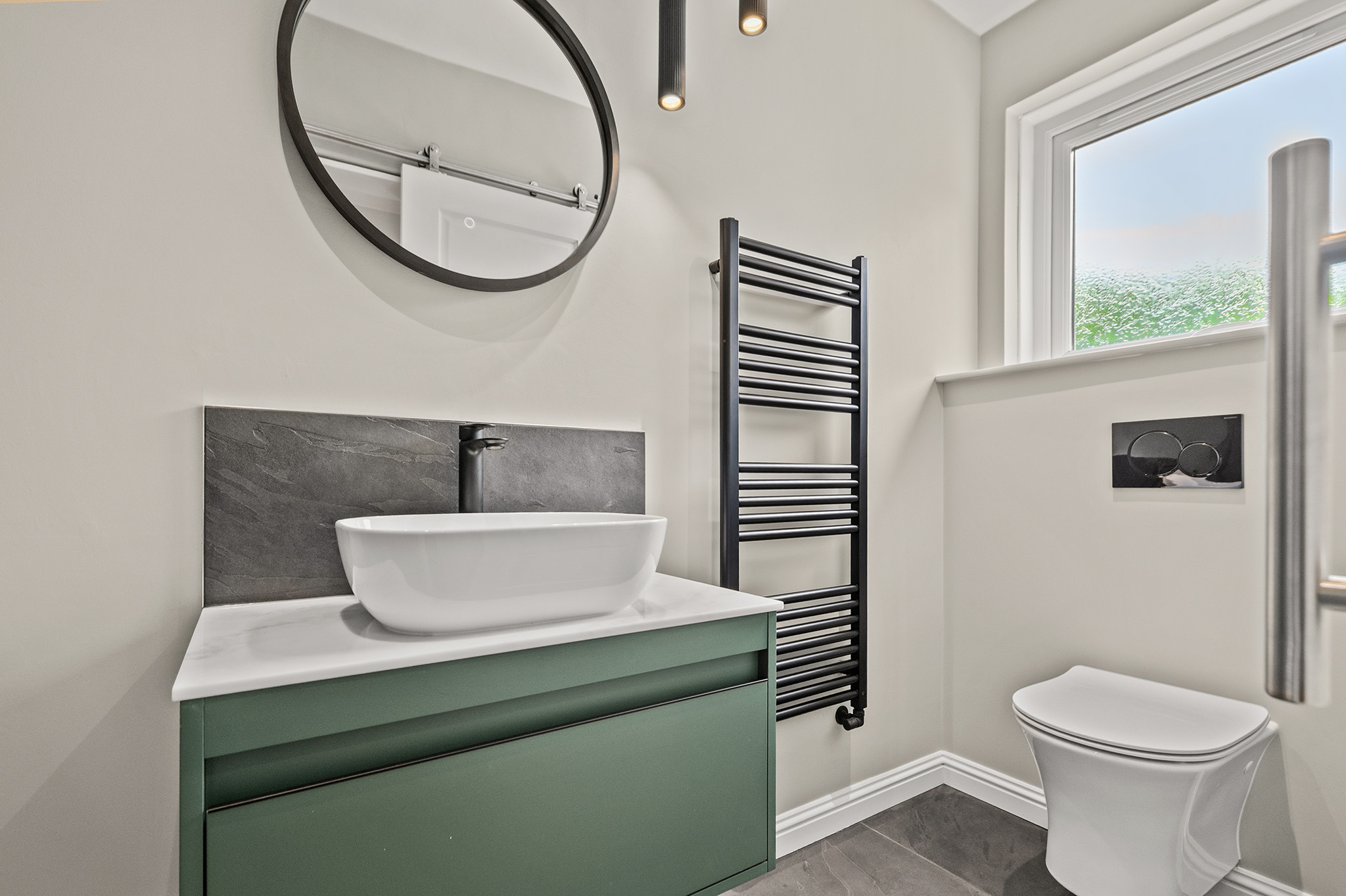 Bathroom at Auchterarder with a wall hung green vanity, countertop basin and round mirror