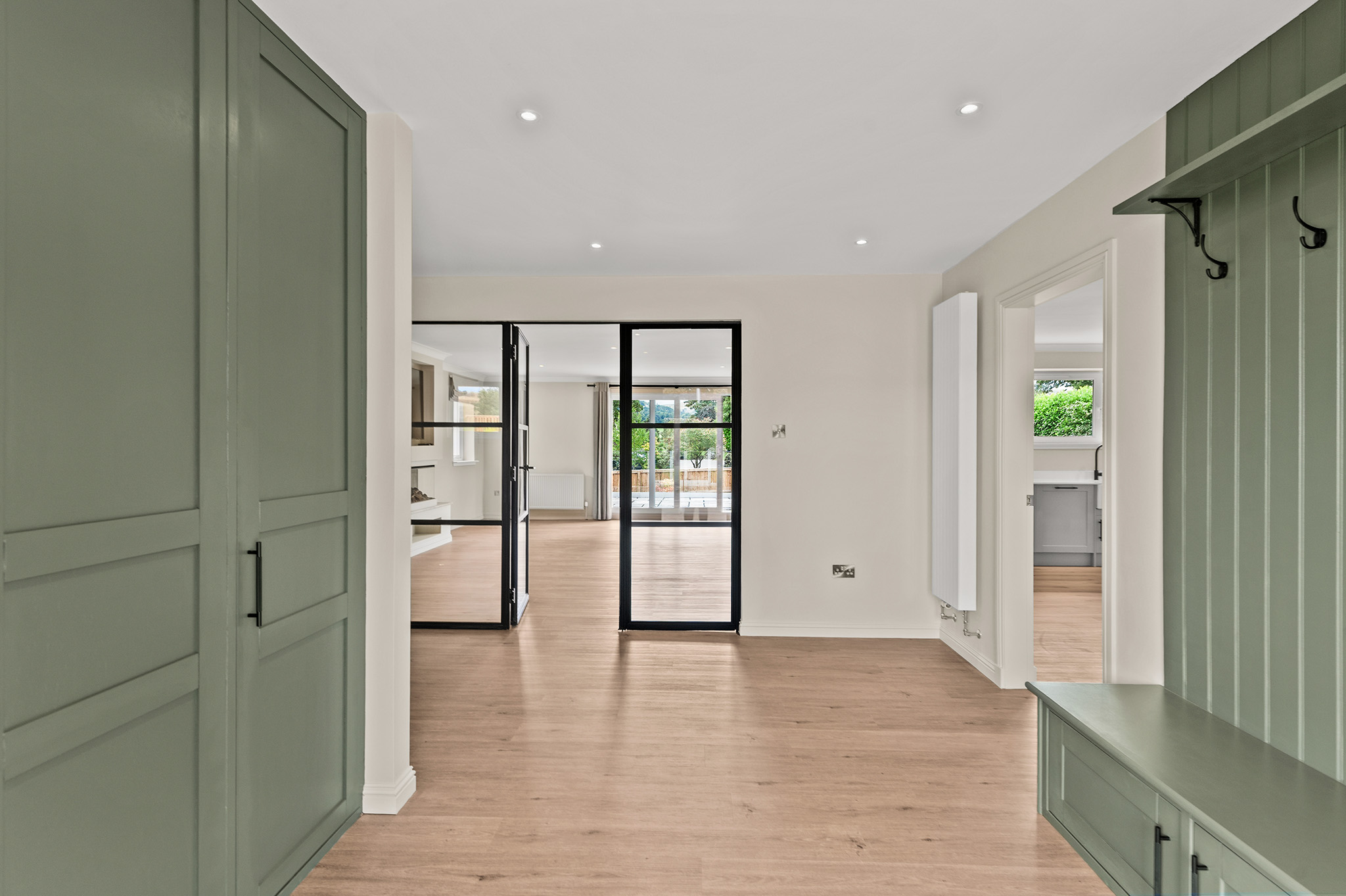 Boot room at Auchterarder with a fitted bench, coat hooks and panelled joinery in sage green