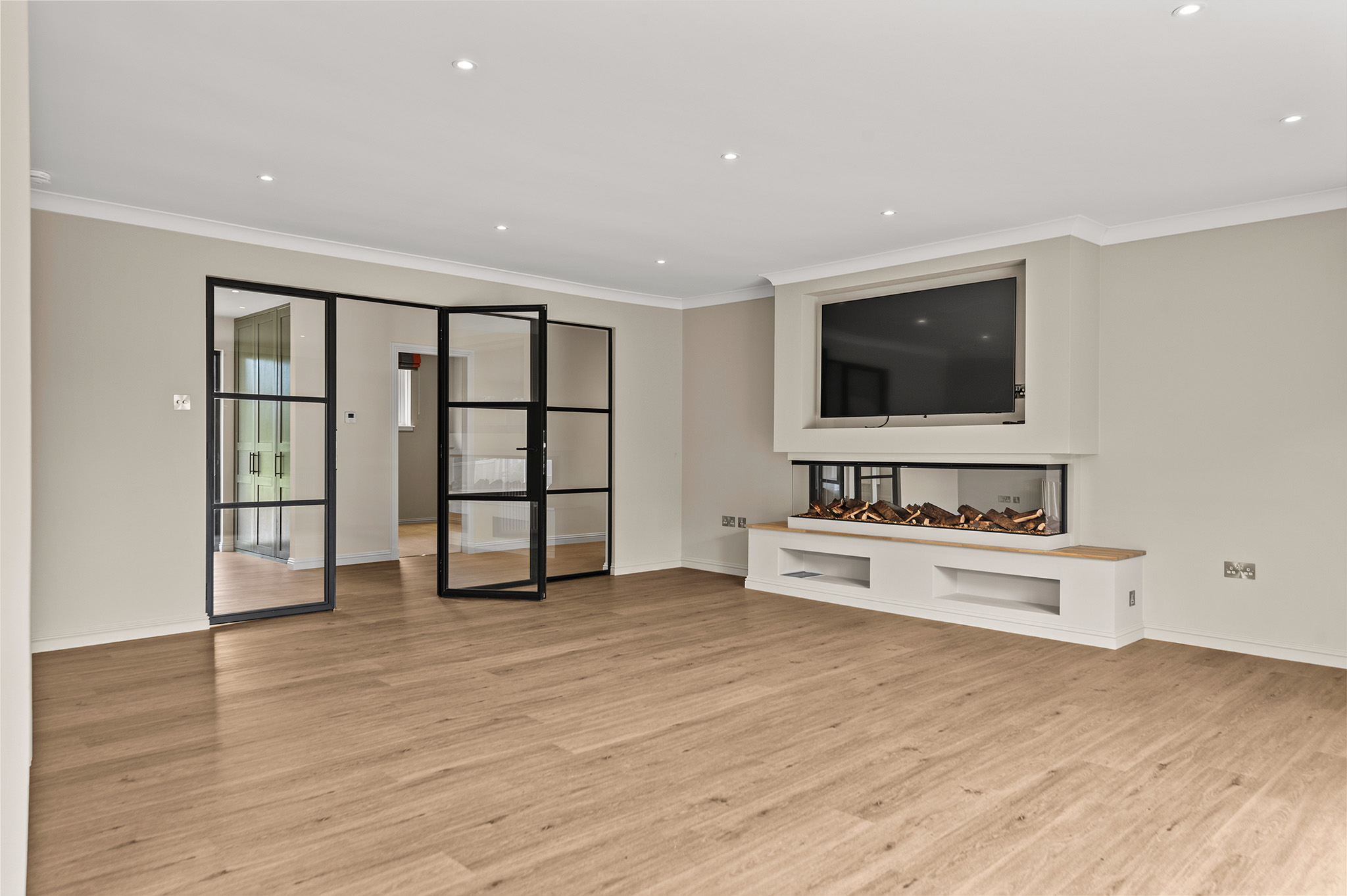 Living room at Auchterarder with a media wall, inset fire and Crittall-style glazed doors