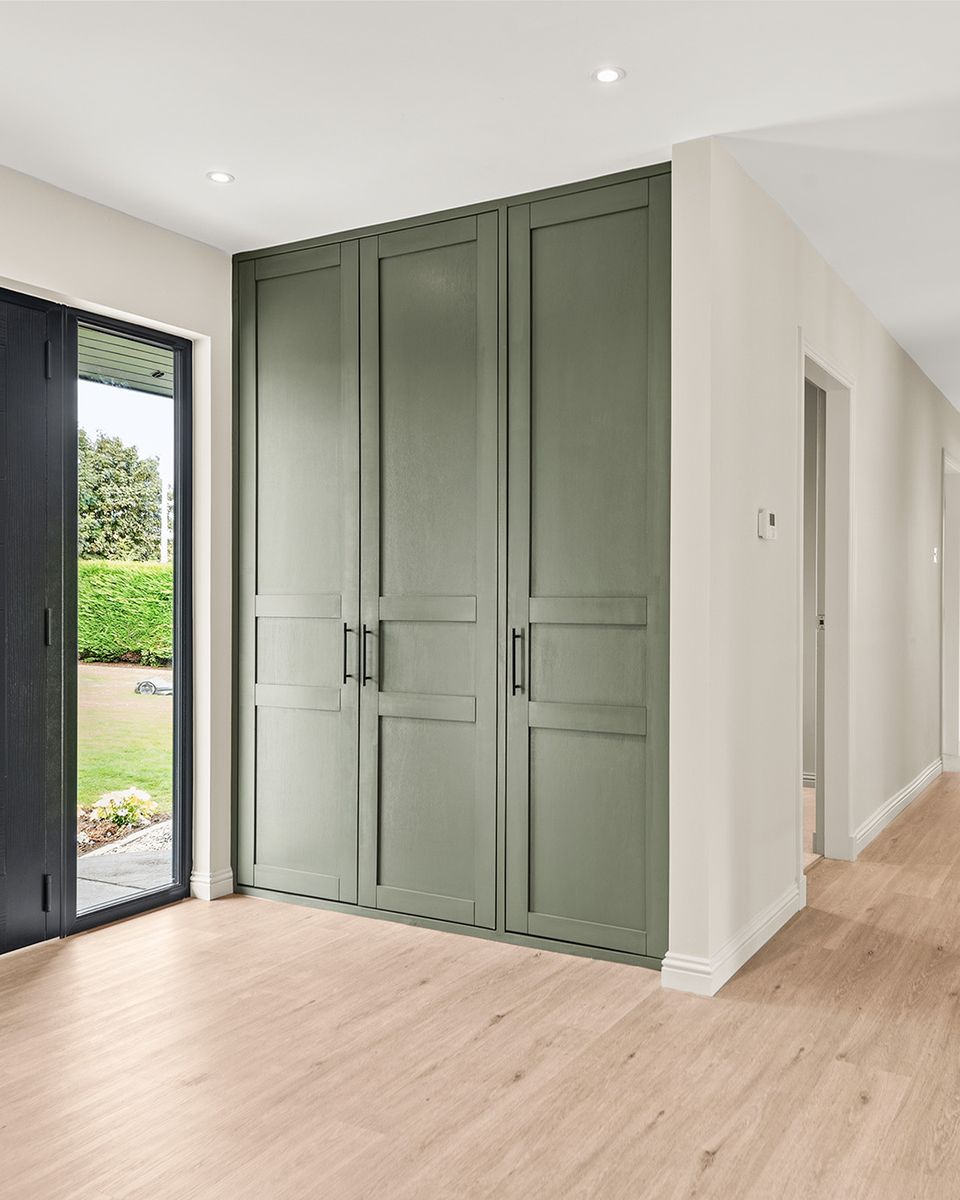 Full-height fitted cupboards painted sage green beside the front door of a house in Auchterarder